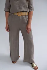 Pantalón de lino color visón, de corte recto y tiro medio. Incluye cinturón beige de soga con hebilla circular de madera.