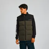 Chaleco acolchado Caterpillar con diseño bicolor en negro y verde oliva. Presenta cierre frontal completo, cuello alto, bolsillos laterales con cierre y logo de la marca estampado en el pecho.