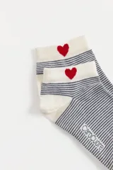 Pack de dos pares de medias soquete marca Caro Cuore. Un par es de color gris melange con estampado de corazones rojos y flores negras, y el otro par es de color crema con rayas horizontales finas en gris y un corazón rojo bordado en el talón.