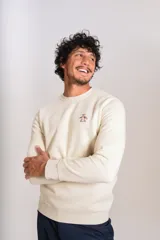 Buzo de cuello redondo color crudo, con detalle de logo bordado en el pecho, mangas largas y puños elastizados.