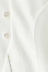 Blazer de botonadura sencilla en tejido efecto neopreno color blanco. Modelo de hombros caídos con escote redondo, botones hasta la cintura y corte acampanado de cintura a bajo.