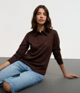 Blusa tipo polo de manga larga, confeccionada en tejido interlock de algodón y poliéster. Presenta cuello clásico con cierre frontal de botones y diseño básico liso.