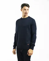 Buzo tejido de punto con cuello redondo, puños y ruedo acanalados. Presenta un diseño clásico y minimalista con un pequeño aplique de marca en el ruedo.