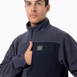 Buzo polar de media cremallera Merrell, confeccionado en microfleece de poliéster reciclado. Presenta cuello alto, bolsillo frontal con cierre y refuerzos en nylon ripstop en la zona superior del pecho. Cuenta con puños y basta elásticos para un ajuste térmico óptimo.