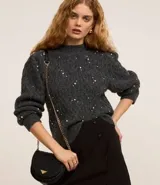 Buzo de tricot texturizado color gris con perlas blancas aplicadas. Tiene mangas largas abullonadas y cuello redondo.