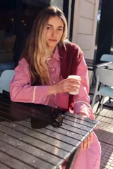 Pijama de dos piezas de algodón a rayas celestes y blancas, compuesto por una camisa de manga larga con botones y ribetes marrones, y un pantalón largo de corte recto con elástico en la cintura.