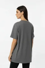 Remera de algodón de manga corta y cuello redondo, con diseño holgado y estampado frontal con motivos florales y texto.