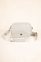 Cartera tipo bandolera de diseño trenzado, con correa ajustable y desmontable de cinta técnica. Cuenta con cierre superior y detalle de aplique metálico en el frente.