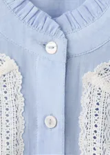 Camisa celeste de algodón con cuello mao, diseño recto, mangas largas abotonadas y detalles bordados con terminaciones festoneadas.