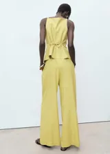 Pantalón de tiro alto color amarillo con sutil diseño de rayas verticales, de corte recto y largo, con bolsillos laterales y cierre frontal de botón y cremallera.