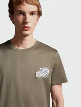 Remera de algodón color verde oliva, con cuello redondo y parche con logo de la marca en el pecho.