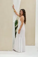 Vestido largo blanco de lino, con tirantes finos para anudar en los hombros, escote en V y falda larga con volante inferior.