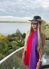 Vestido corto sin mangas con diseño bicolor, presentando una mitad en color rojo y la otra en color violeta. Posee un corte recto y holgado con cuello redondo.