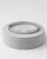 Esclava rígida de acero inoxidable con diseño abierto y detalles de circonias engastadas en una de sus bandas.
