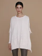 Mantela sweater color crudo, con cuello redondo y mangas largas con flecos. Tejido de punto con diseño de trenzas y bolsillos frontales.