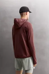 Sudadera técnica color bordó con capucha, cierre frontal completo y bolsillo en el pecho con cremallera oculta. Tejido elástico con interior efecto polar y estructura waffle. Presenta puños adaptables con ajuste para el pulgar.