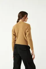 Sweater color camel de punto con diseño de ochos en el frente y mangas, cuello semi alto y corte al cuerpo.