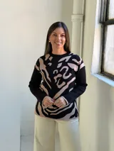 Sweater de tejido de punto con diseño estampado abstracto en tonos negro y beige, de cuello redondo y manga larga.