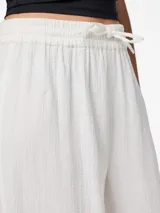 Pantalón blanco de tejido plano de algodón orgánico, corte ancho, tiro alto, largo hasta el tobillo, cintura elástica con cordón ajustable.