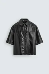 Sobrecamisa de corte relajado confeccionada en tejido efecto piel, con cuello solapa, manga corta y cierre frontal con cremallera. Presenta un bolsillo plastrón en el pecho y bajo con aberturas laterales.
