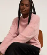 Suéter de punto color crema con cuello redondo y mangas largas ajustadas. Modelo slim alargado con efecto de pelitos.