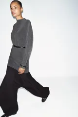 Vestido corto de tejido suave color gris oscuro, con cuello redondo y manga larga. Incluye un cinturón fino de efecto piel con hebilla metálica dorada.