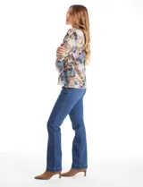 Buzo de hilado fino con cuello redondo y mangas largas. Presenta un estampado floral en tonos grises, azules y ocres, con detalle de botones decorativos en el lateral inferior.