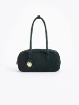 Cartera de estructura firme confeccionada en cuero descarne vacuno, con diseño rectangular y manijas fijas. Presenta un logo grabado en el frente y un dije metálico colgante en forma de vaquita de San Antonio.