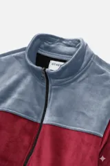 Campera de polar con cierre frontal completo, cuello alto y diseño bicolor en gris y negro. Cuenta con bolsillos laterales y puños elásticos.