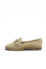 Mocasín de gamuza color beige, con detalle de hebilla metálica dorada en el empeine, costuras visibles y suela plana.