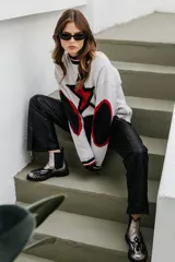 Sweater tejido en lana con viscosa y poliéster, color gris claro, con diseño de estrella roja en el pecho y parches negros en los codos.