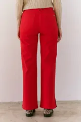 Pantalón color beige de corte recto, confeccionado en algodón y spandex. Presenta tiro medio y cierre frontal con botón y cremallera. Incluye cinturón marrón con hebilla plateada.