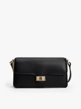 Cartera tipo bandolera de color negro, con acabado liso y solapa frontal. Presenta herrajes metálicos dorados, incluyendo un cierre con el monograma TH y un logo de Tommy Hilfiger en bajo relieve.