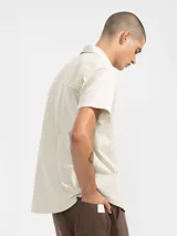 Camisa azul de manga corta confeccionada en algodón ligero con textura waffle. Presenta corte cuadrado, bolsillo en el pecho y botones de coco grabados con el logo de Polonio.