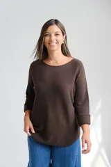 Sweater de punto color marrón chocolate, con escote redondo a la base y mangas tres cuartos con puños vueltos. Presenta un corte holgado con ruedo redondeado.
