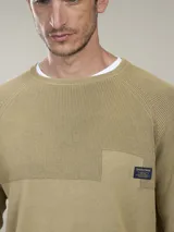Sweater de algodón con cuello redondo, diseño de tejido combinado con textura acanalada en la parte superior y bolsillo frontal pequeño con etiqueta decorativa.
