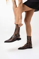 Chatas de cuero negro con punta fina, diseño destalonado y tira con hebilla metálica plateada. Presentan apliques de tachas plateadas en toda la superficie.