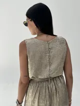 Conjunto de musculosa y pantalón palazzo color dorado brillante. La musculosa es sin mangas y el pantalón es de corte ancho con cintura alta.