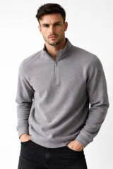 Buzo de polar negro con cuello alto y cierre frontal parcial, de manga larga y diseño holgado.