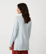 Suéter de tejido de punto color beige con cuello alto, mangas con corte raglán y puños y ruedo acanalados. Presenta un diseño clásico y cómodo con el ruedo trasero ligeramente más largo.