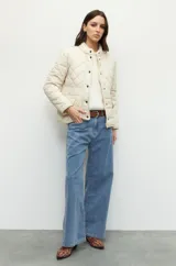 Campera capitoneada color beige, de cuello alto, con bolsillos de solapa y botones metálicos.