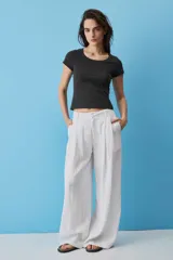 Pantalon blanco de lino de pierna ancha y tiro alto, con pinzas frontales y bolsillos laterales.