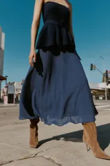 Falda midi azul oscuro, de tiro alto, con corte evasé y textura arrugada o plisada. Presenta un forro interior y cierre lateral oculto.