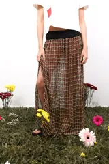 Falda larga de corte recto con caída fluida, confeccionada en tejido de telar con diseño a cuadros. Presenta una pretina tejida en punto elástico y un tajo lateral que aporta movimiento.