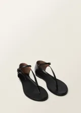 Sandalias planas negras de cuero, con tira delantera y tira con hebilla al tobillo.
