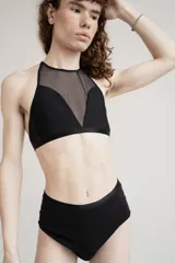 Top negro confeccionado en lycra y tela de malla semitransparente, con diseño de cuello halter y ajuste posterior.