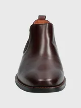 Bota tipo Chelsea de cuero en color bordó, con paneles laterales elásticos y suela de goma negra.