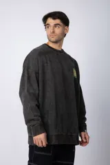 Buzo de cuello redondo y corte oversize, confeccionado en tela friza con efecto de teñido artesanal desgastado. Presenta un estampado pequeño en color verde lima en el pecho y una etiqueta pequeña en el puño.