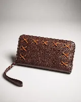 Billetera rectangular de cuero marrón con cierre perimetral y correa de muñeca. Presenta un diseño decorativo con costuras en forma de X en la parte frontal.