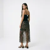 Falda midi de tul negro con diseño geométrico y arabescos bordados en hilo negro y lentejuelas. Presenta una silueta recta con transparencia y forro corto integrado.
